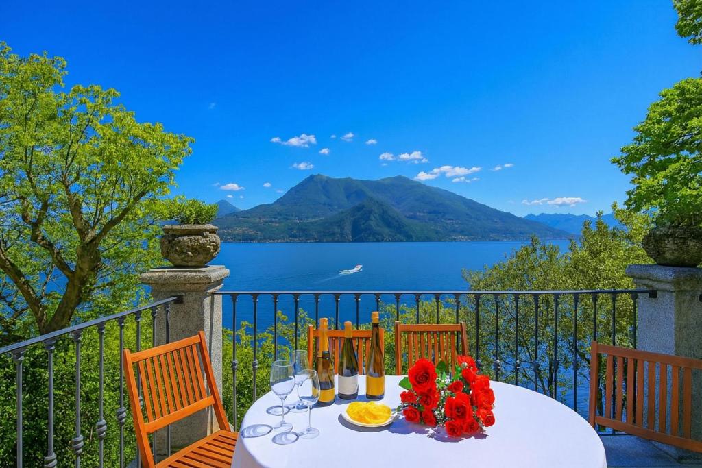 a white table with red flowers on a balcony at Villa Lucia Varenna in Varenna