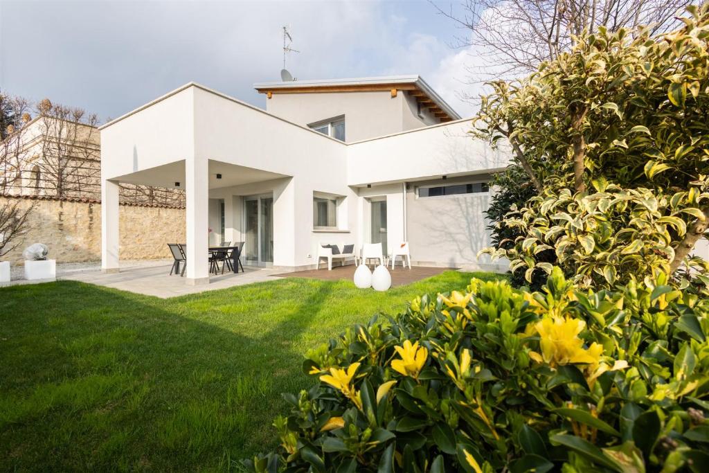 a white house with a yard with yellow flowers at IseoLakeRental - Villa Edwige in Provaglio d'Iseo