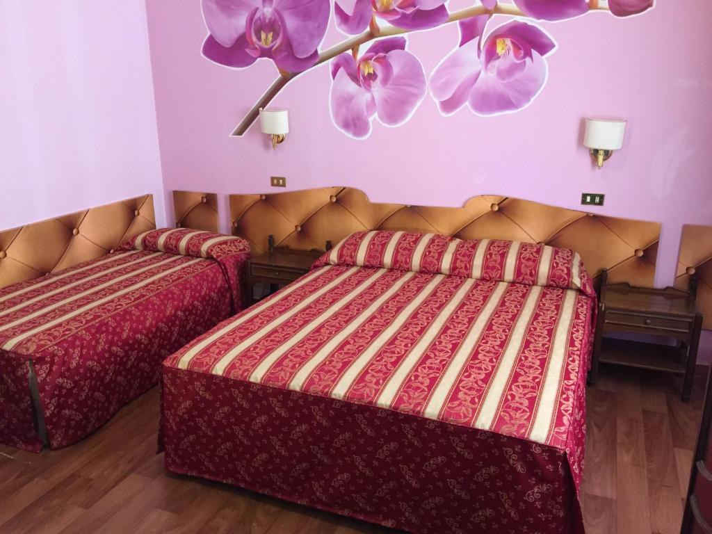2 łóżka w pokoju z fioletowymi ścianami w obiekcie Hotel Gabriele w Rzymie
