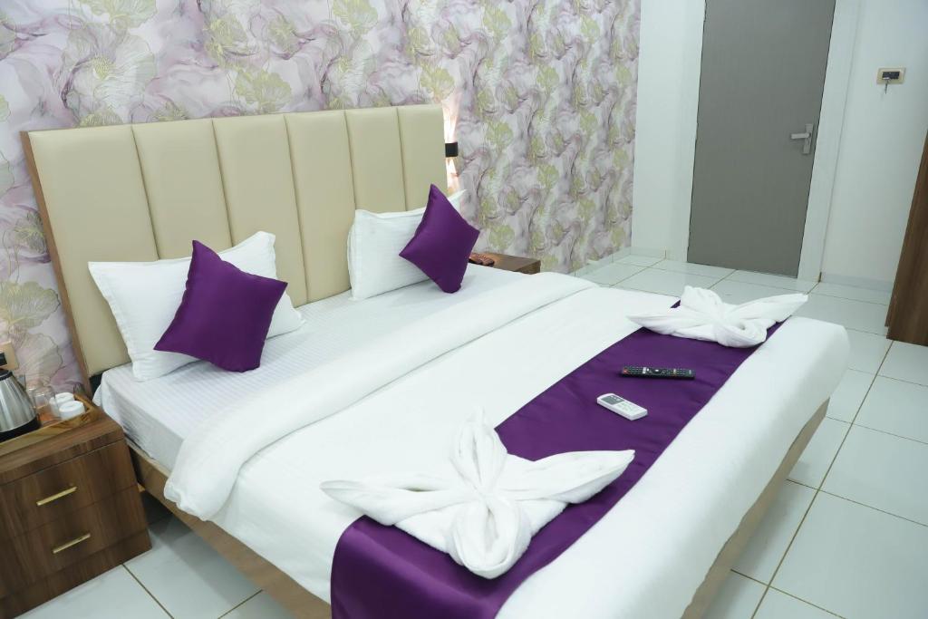 a large bed with purple and white pillows at Hotel White House in Navi Mumbai