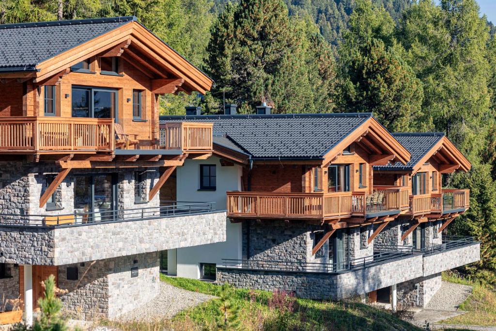 a row of wooden homes on a hill with trees at Turrach Lodges by ALPS RESORTS in Turracher Hohe