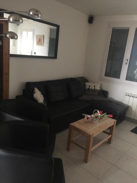 Maison Le Plai-Syl في Volonne: غرفة معيشة مع أريكة سوداء وطاولة