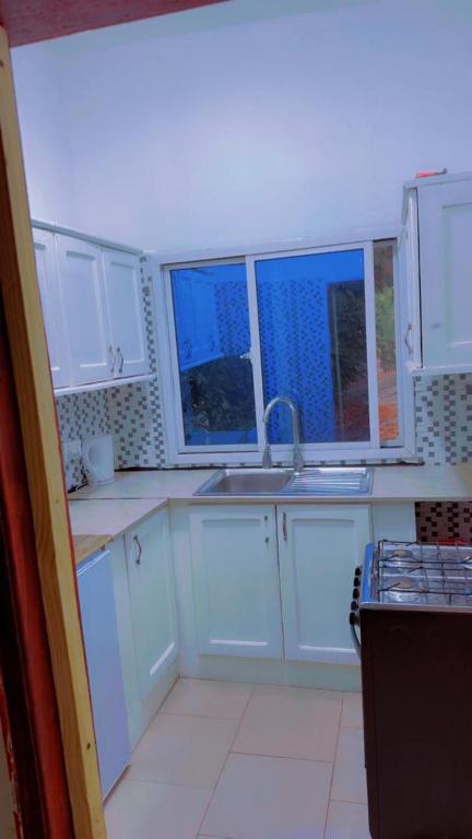 a kitchen with white cabinets and a sink and windows at A & A Apartments in Serekunda