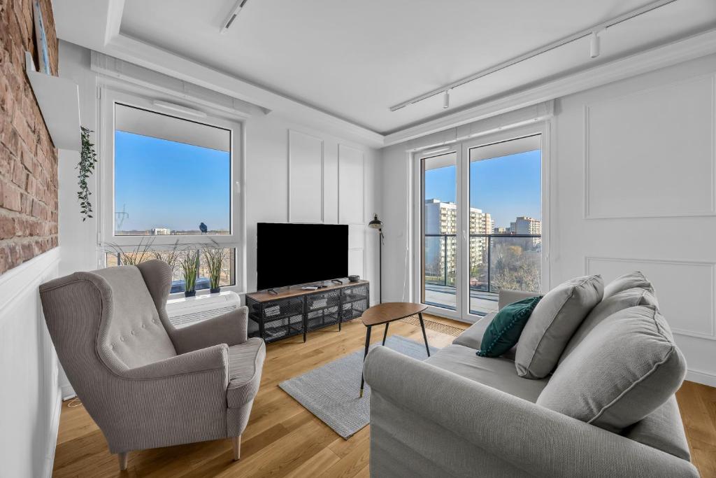 a living room with two chairs and a television at Mehoffera Superior Apartment by BookingHost in Warsaw