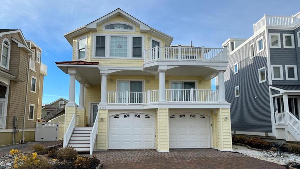 a large yellow house with a balcony on top of it at Bayside Home With 4 Bedrooms And Elevator in North Beach Haven
