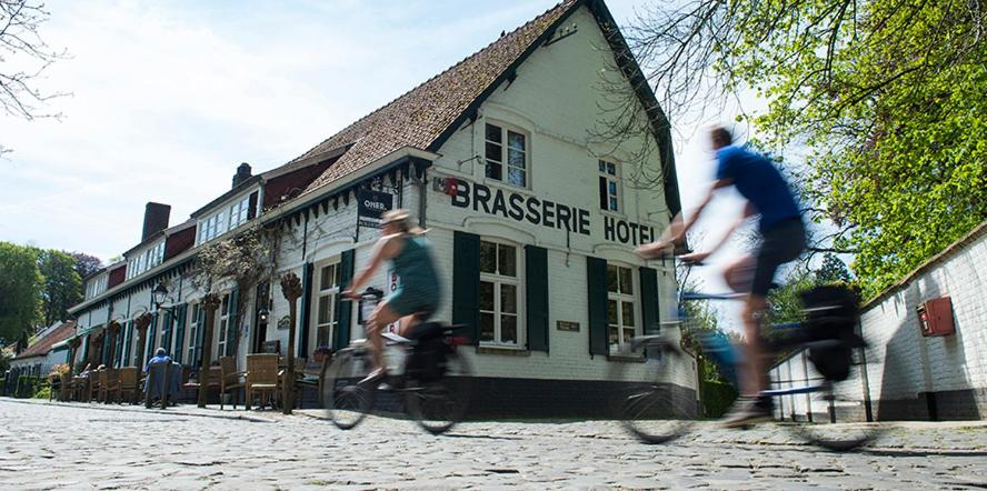 duas pessoas a andar de bicicleta em frente a um edifício em Hotel In't Boldershof em Deurle