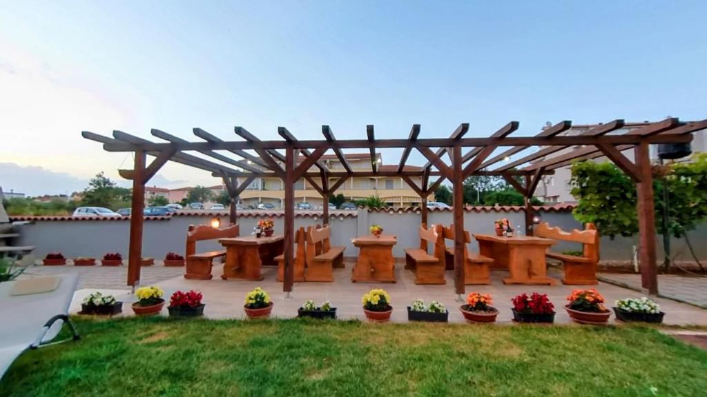 a wooden pergola with tables and chairs on a patio at Apartmani Daria in Medulin