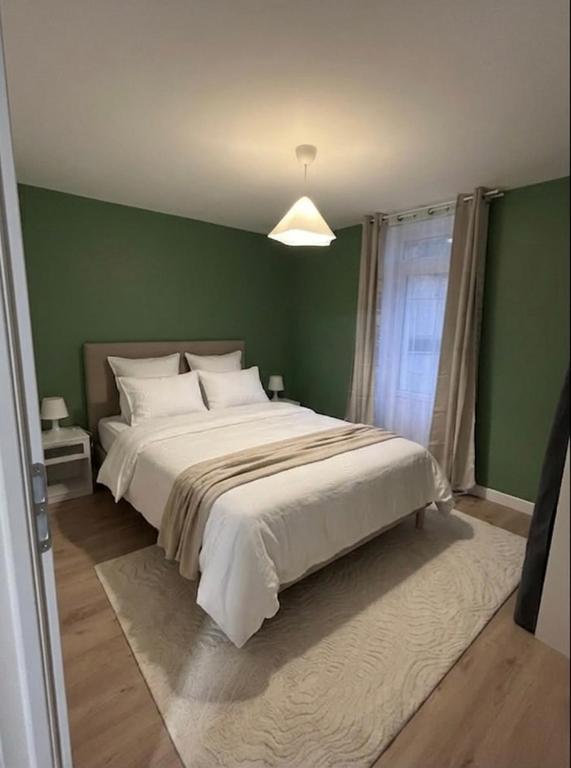a bedroom with a large white bed with a green wall at La parenthèse Jurassienne in Orgelet