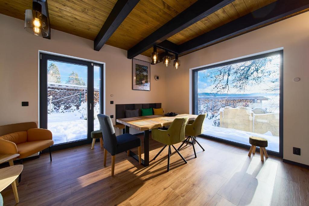 a dining room with a table and chairs and large windows at Apartmány U Kovárny in Horní Blatná