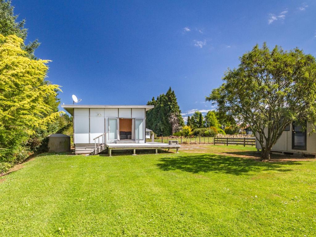 a small white house with a picnic table in a yard at Sweet Rangataua - Rangataua Bach in Ohakune