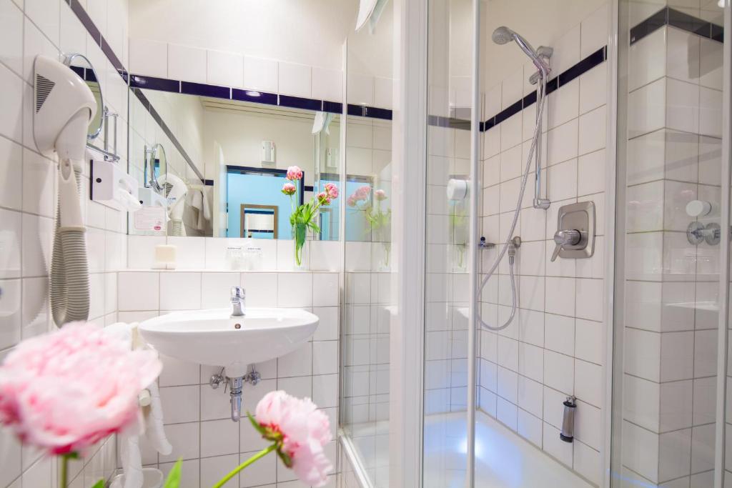 a white bathroom with a shower and a sink at Hotel Senator Marina in Wedel