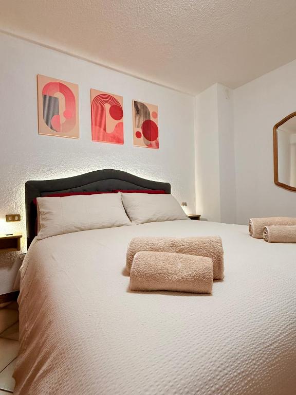 a bedroom with a large white bed with art on the wall at Incentro in Grosio