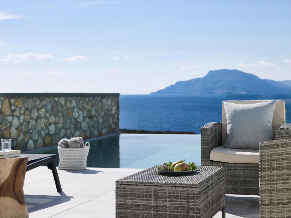 a patio with a chair and a bowl of fruit on a table at Arpathea Villas in Foiníkion