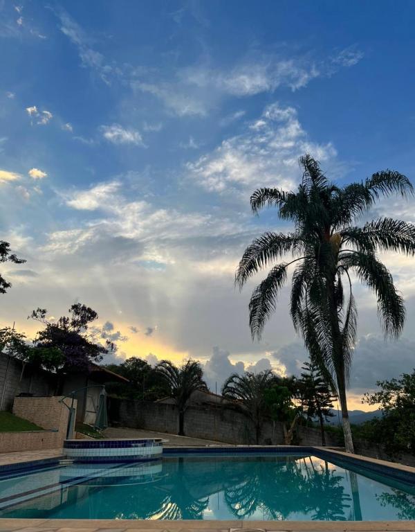 a palm tree and a swimming pool with a palm tree at Recanto do Joao Sta Isabel in Santa Isabel