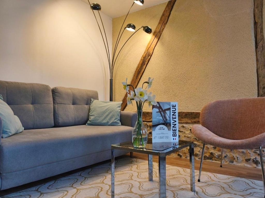 a living room with a couch and a table and two chairs at Calme petite maison normande au coeur de Breteuil in Breteuil-sur-Iton