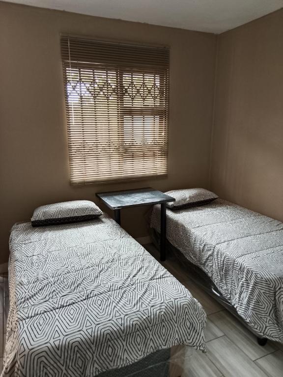 a room with two beds and a window and a table at AMASHIYA flats in Richards Bay