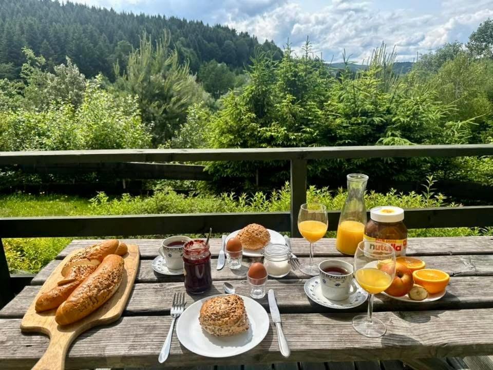 a table with bread and oranges and glasses of orange juice at Domki przy lesie 300m od jeziora 509-619-803 in Zawóz