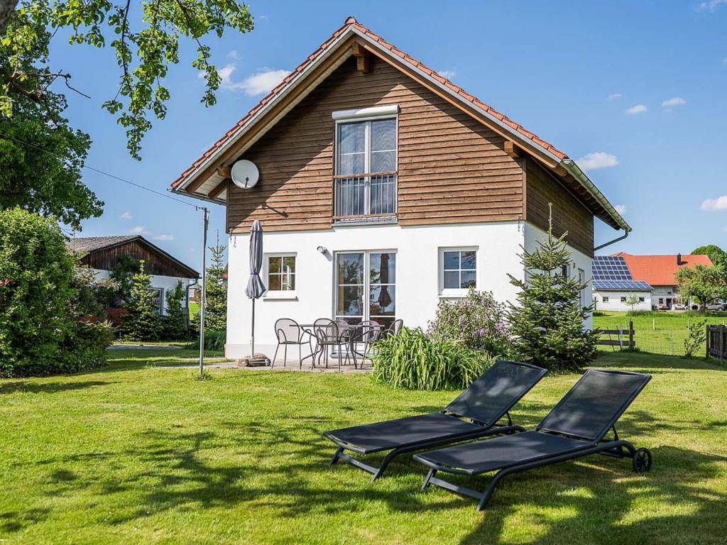 two chairs sitting in the grass in front of a house at Ferienhof Rummel Allgäu - verschiedene Unterkünfte für bis zu 6 Personen - Sauna, Spielplatz, Lagerfeuer & Frühstücksservice - ideal für Familien- und Aktivurlaub in Argenbühl