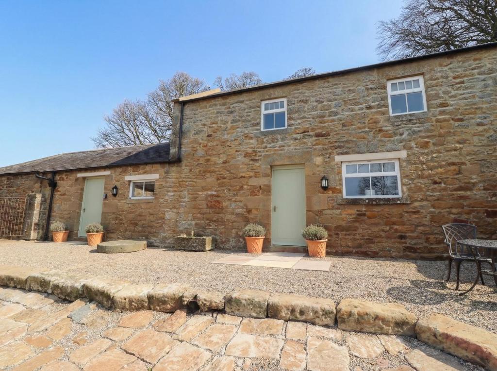 a brick house with a patio in front of it at Cragg Lodge in Hexham
