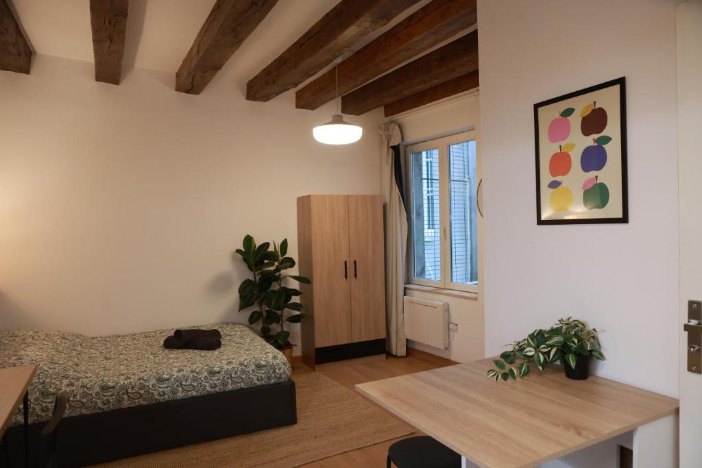 a bedroom with a bed and a table and a window at Les Écuries - Studio Hyper Centre & Bouffay in Nantes