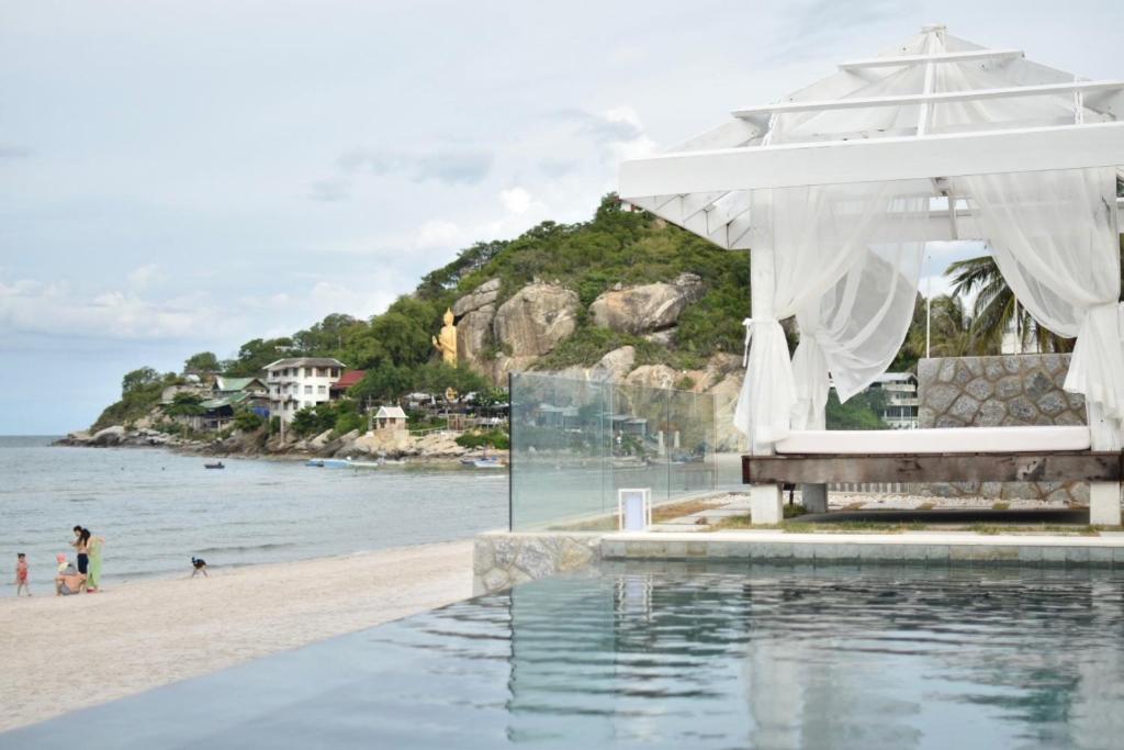 a swimming pool next to a beach with a house at Villa Baan Loukpla in Hua Hin