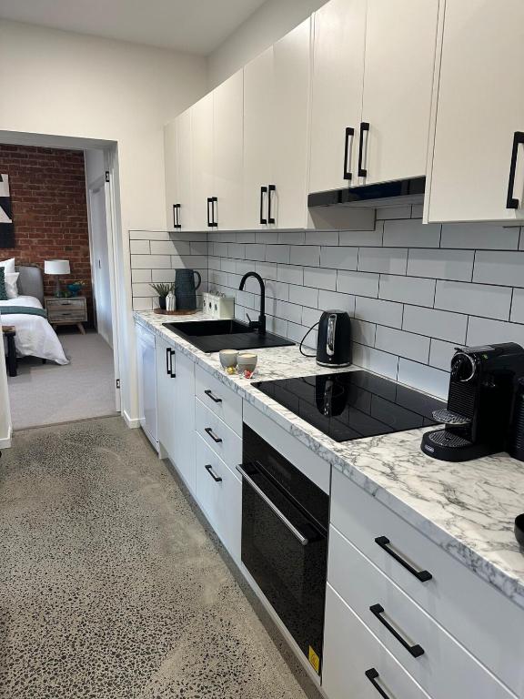 a kitchen with white cabinets and a sink at Modern Soho Pad with Sunny Deck in West Hobart