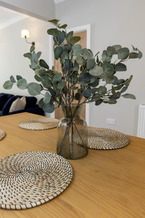 a wooden table with a vase with a plant in it at Eller Cottage in Windermere