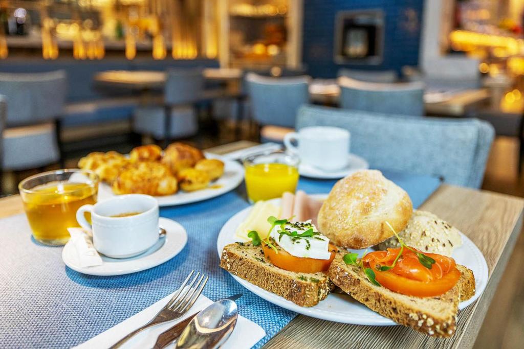 A breakfast table with open-faced sandwiches, pastries, fruit juice and coffee.