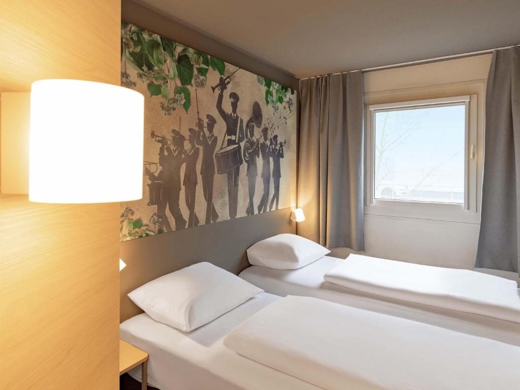 two beds in a room with a painting on the wall at B&B HOTEL Gießen-Linden in Gießen