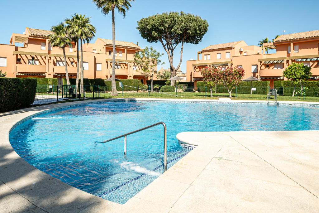 a swimming pool in front of a building with palm trees at Jardín del Golf2 9 1A in Novo Sancti Petri