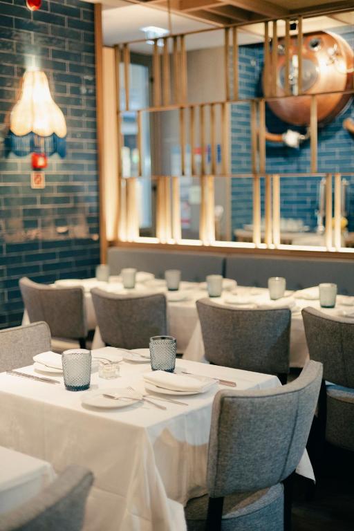 A formally set dining room with white tablecloths and upholstered chairs.