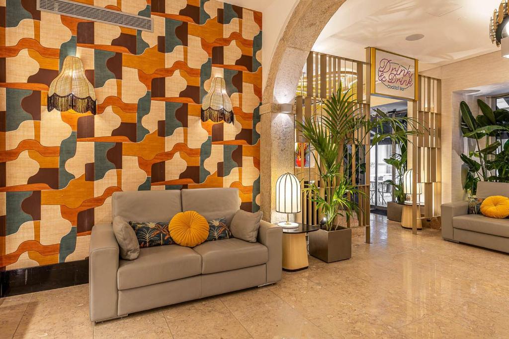 A lounge seating area combines a sofa, bold geometric wall covering, plants, and warm decorative lighting.