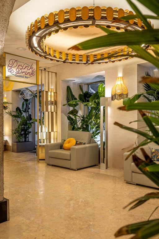 A plant-filled hotel lounge with cream sofas, marble flooring and a statement circular light.