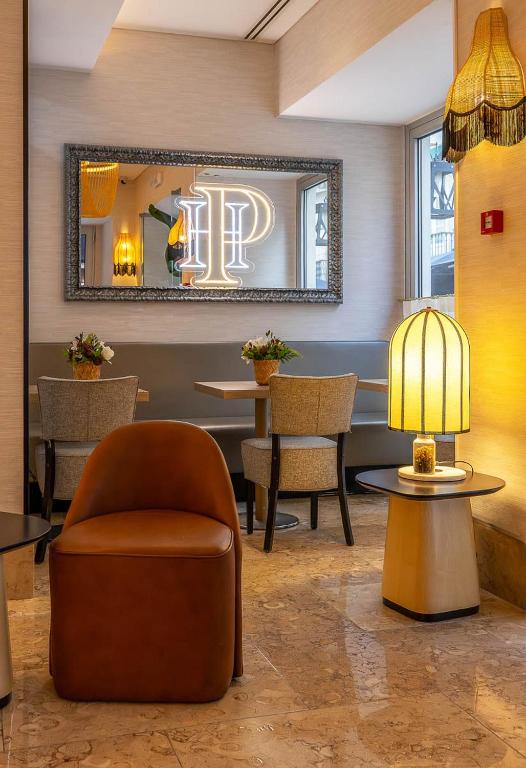 A compact lobby seating area combines a rust-colored armchair, café tables and statement lighting.