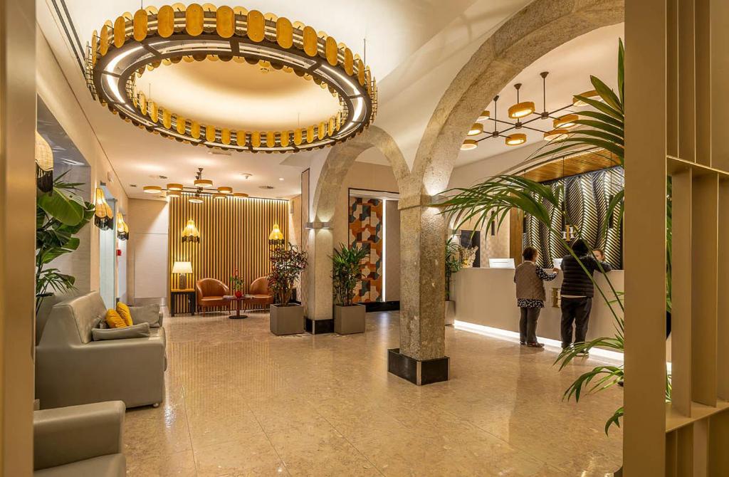A polished lobby uses oversized circular lighting, stone arches, plants, and upholstered seating.