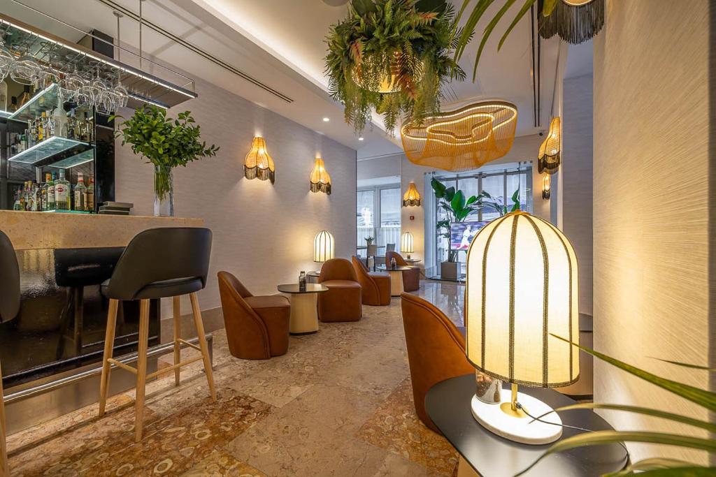 A stylish lobby lounge with a bar, armchairs, plants, and statement lighting.