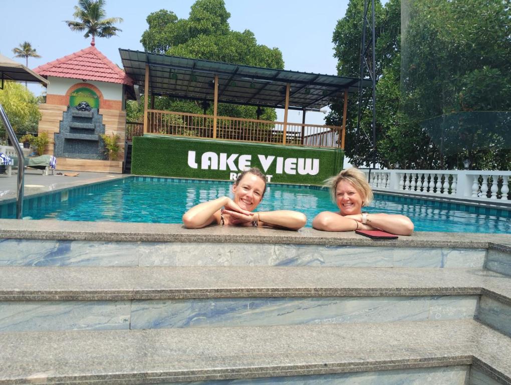 two girls laying on the side of a swimming pool at Lake view Resort cherai in Cherai Beach