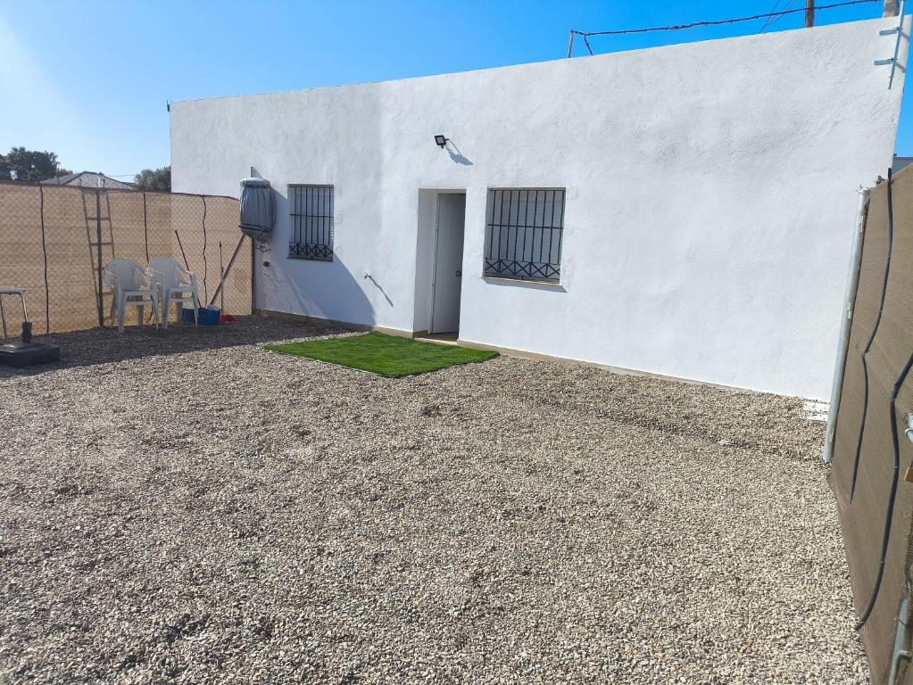 a white building with a door and some grass at Casa Campo Gerena in Sanlúcar de Barrameda