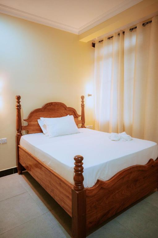 a bedroom with a wooden bed and a window at Al-mendhiry Apartment in Zanzibar City