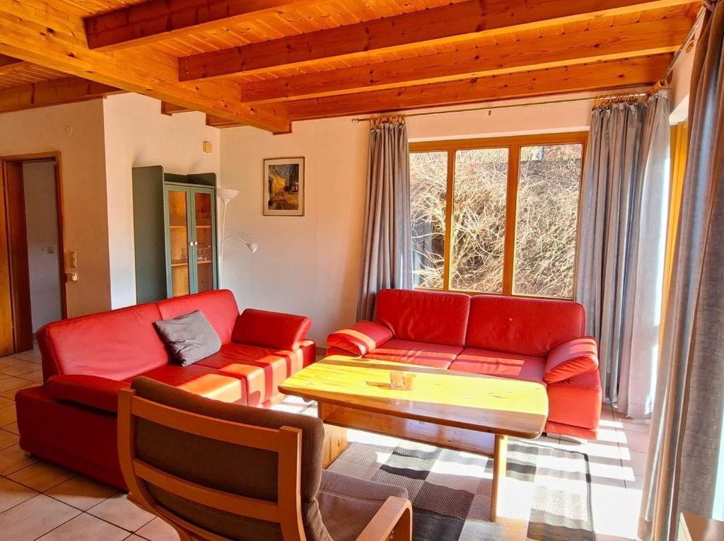 a living room with a red couch and a table at Haus 23 Natur Ferienpark - Gemütlicher Urlaubsort für entspannte Tage im Grünen und in der Nähe von den Externsteinen in Nieheim
