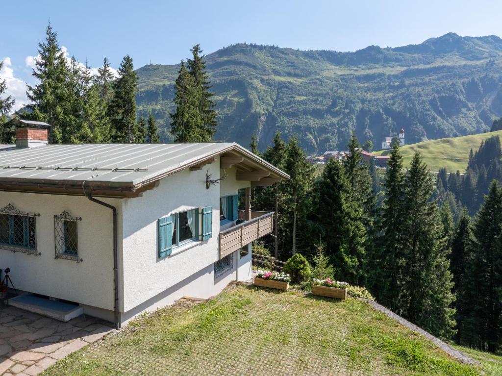 a house on a hill with mountains in the background at Ferienhaus am Waldrand in Damuls