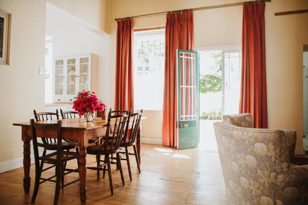 a dining room with a wooden table and chairs at Charming Historical Cottage in Graaff-Reinet