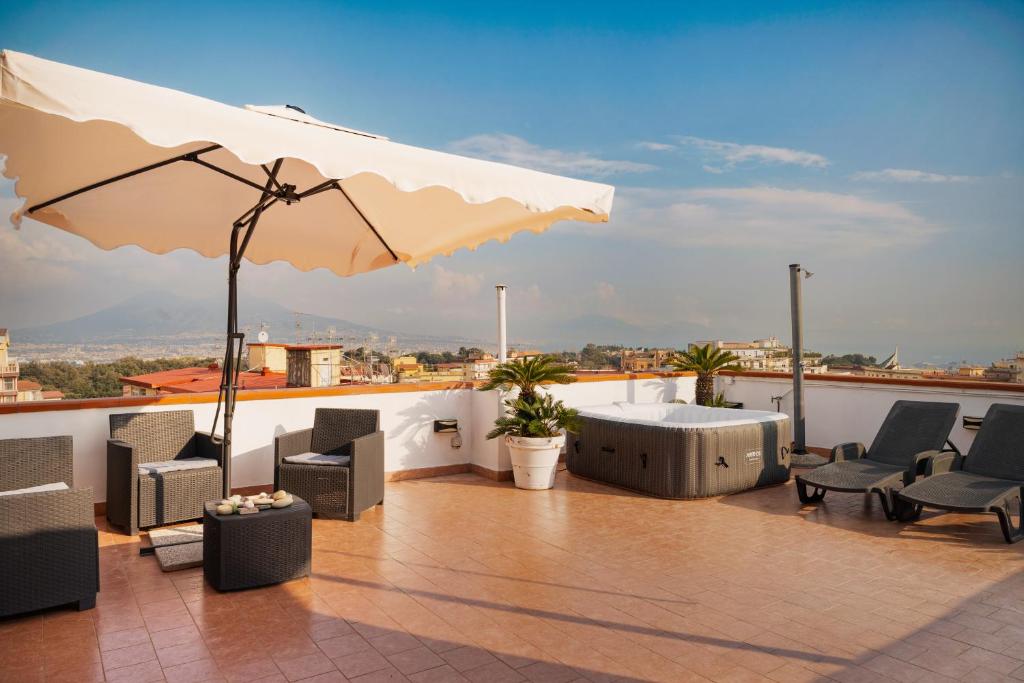 a patio with chairs and an umbrella on a roof at Terrazza vista Vesuvio e Capri con Jacuzzi privata in Naples