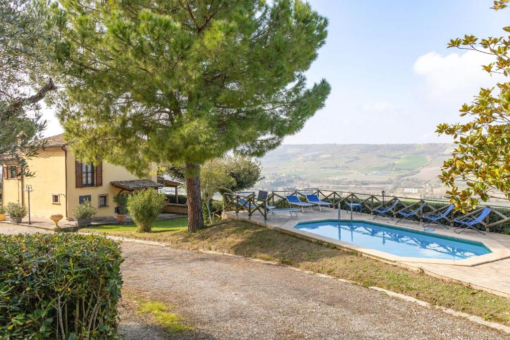 a swimming pool with a tree and a house at Italian Experience-Casale Dolcemare in Campofilone