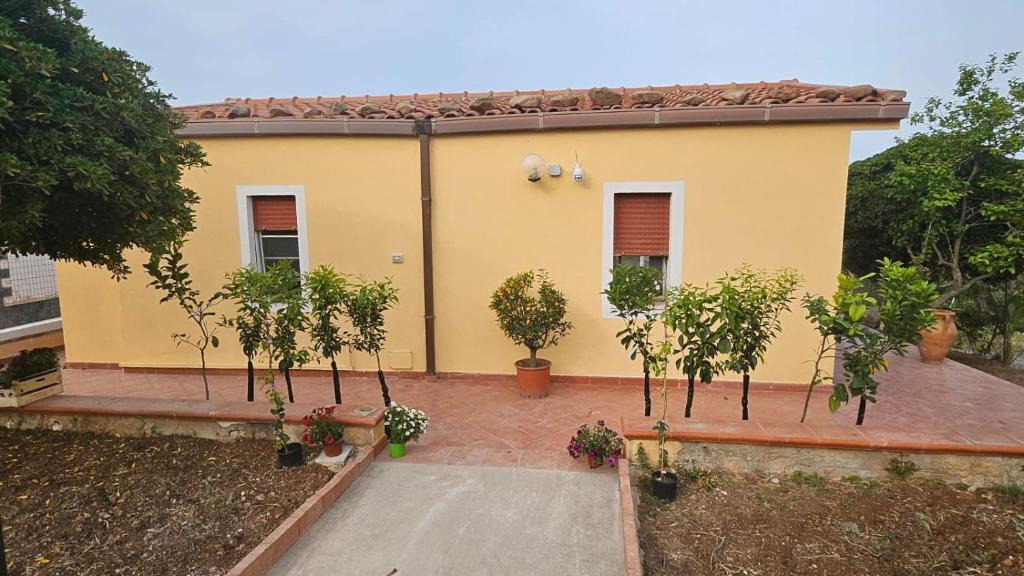 a yellow house with trees in front of it at Donna Pulina Holidays in Pollina