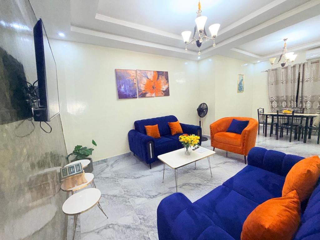 Una sala de estar con sofás azules y sillas naranjas. en House & Food, en Thiès