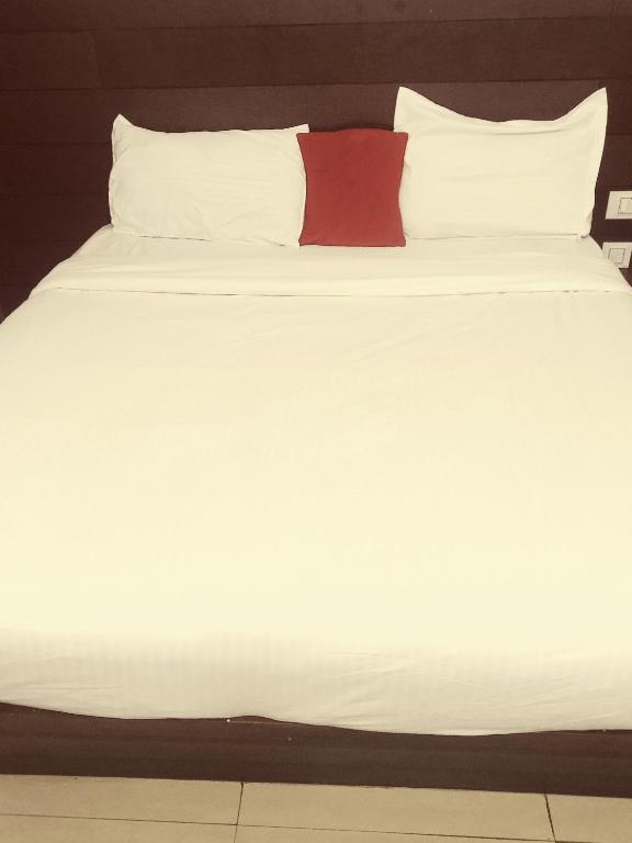 a white bed with a red pillow on it at Hotel Red ark inn in Mohali