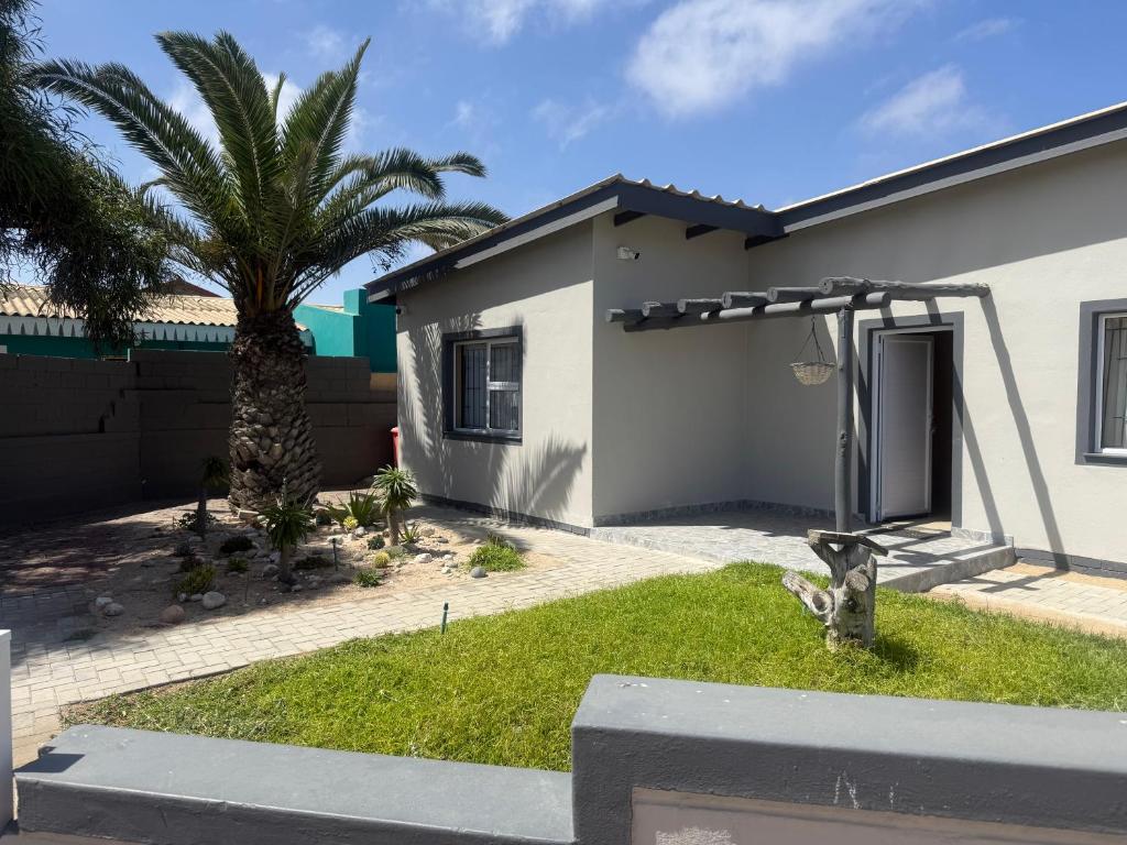 a house with a palm tree in the yard at Casa Palm and Tide self catering accommodation in Swakopmund