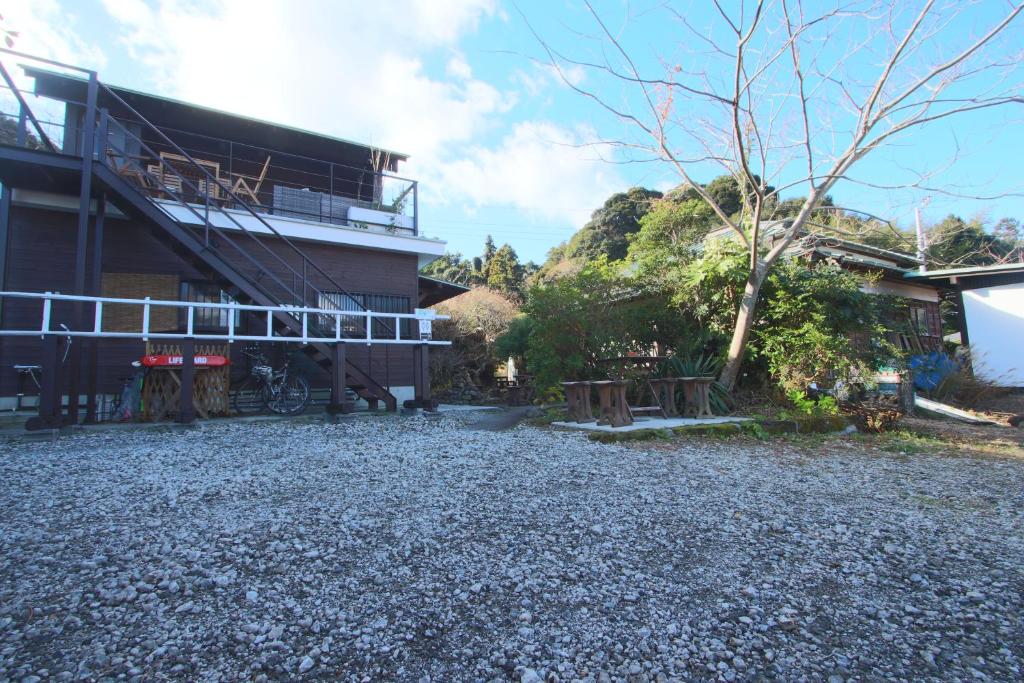 a building with a gravel yard next to a building at Bungee Inn in Minamiizu
