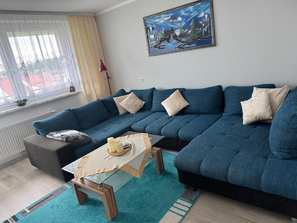 a living room with a blue couch and a table at Apartment 4 rooms 'Bauer' in Korfantów